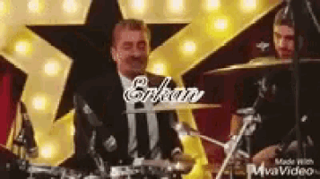 a man in a suit is playing drums on a stage .