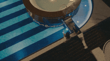 an aerial view of a swimming pool with two people standing on the edge