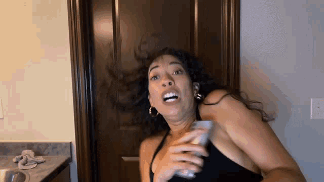 a woman is making a funny face while holding a glass of beer