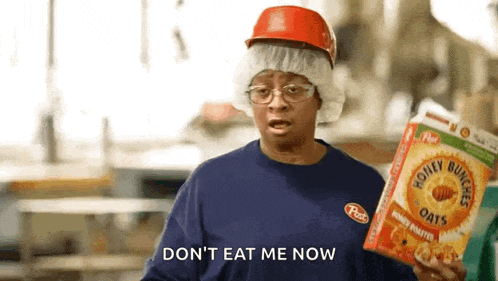 a woman wearing a hard hat and glasses is holding a box of honey bunches of oats