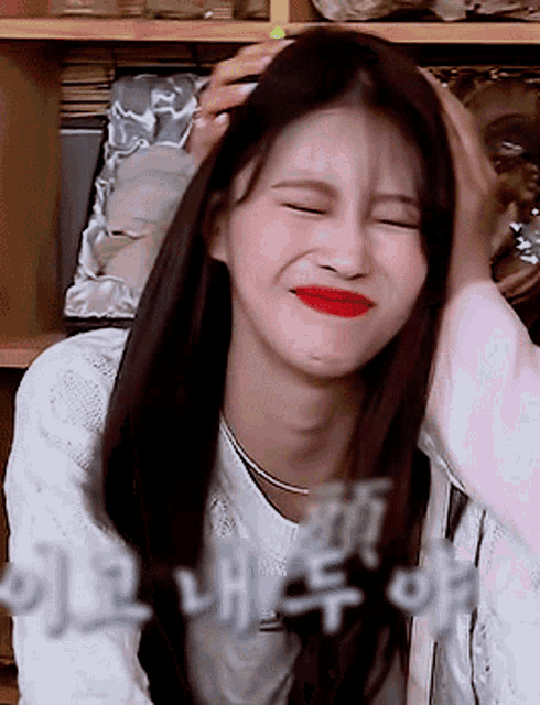 a woman with red lips is smiling and holding her head