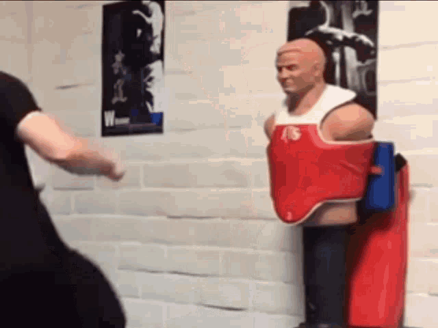 a man is standing next to a mannequin wearing a red and white vest .