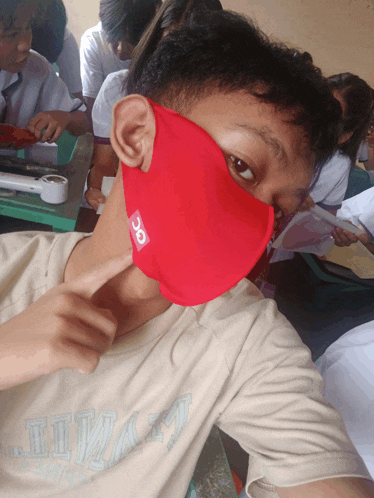 a boy wearing a red face mask with a sticker that says 3c on it