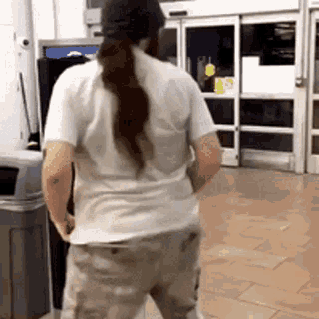 a man with a ponytail is standing in front of a sliding glass door