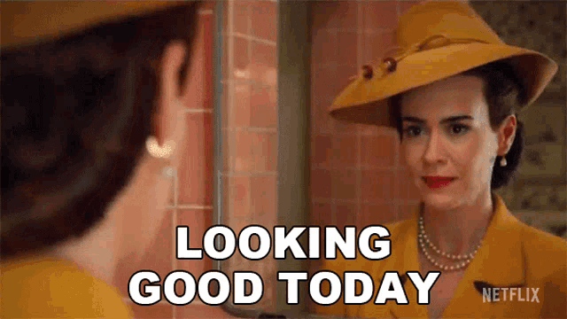 a woman in a yellow hat is looking at herself in a mirror and saying looking good today .
