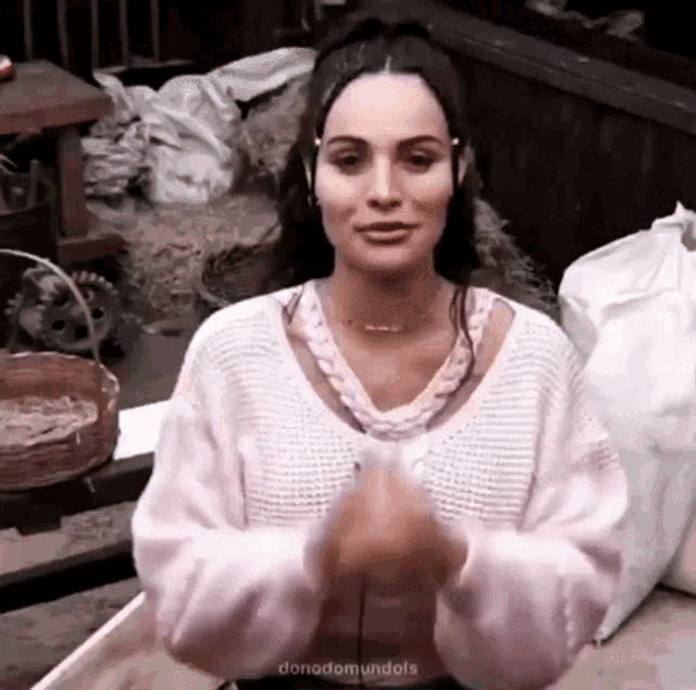 a woman wearing a pink sweater and headphones is standing in front of a table .
