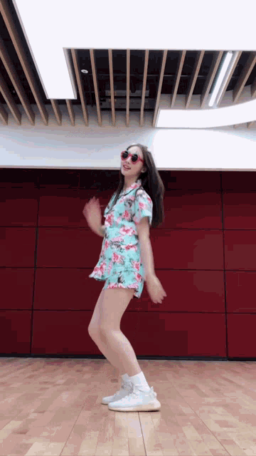 a woman in a floral dress is dancing in a room