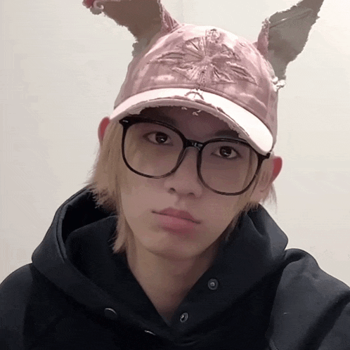 a young man wearing glasses and a pink hat with bunny ears