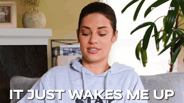 a woman sitting on a couch with the words it just wakes me up behind her