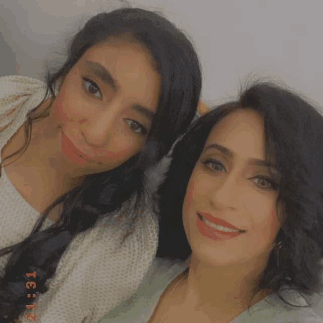 two women are posing for a picture and the time is 21:31