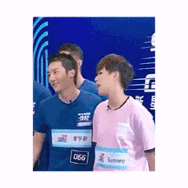 a group of young men are standing next to each other and one of them is wearing a pink shirt with the name summer on it .
