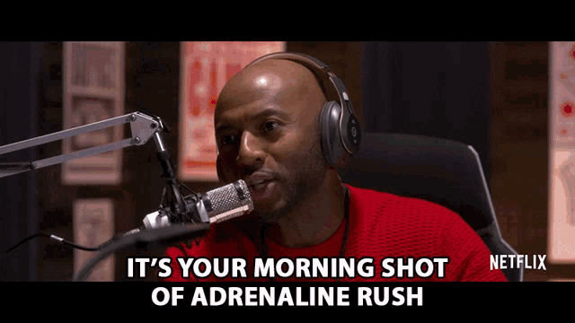 a man wearing headphones is talking into a microphone with the words " it 's your morning shot of adrenaline rush " below him