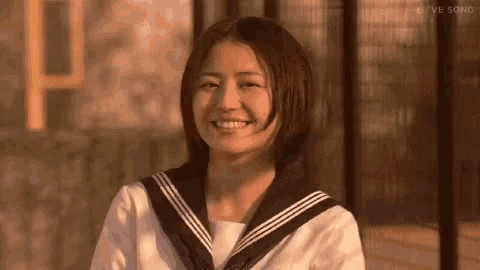 a young woman in a sailor uniform is smiling .