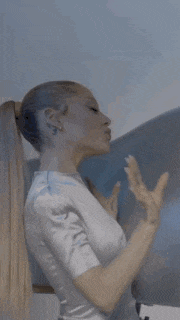 a woman with long hair in a ponytail is making a peace sign .