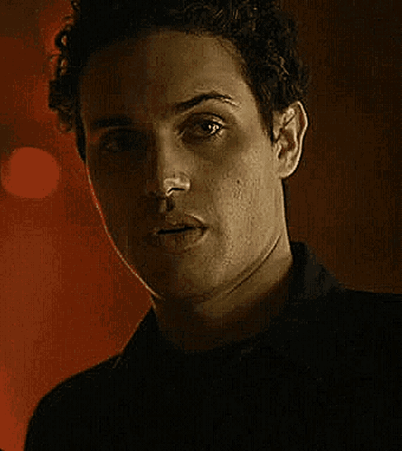 a close up of a young man 's face in a dark room .