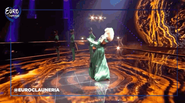 a woman in a green dress is dancing on a stage in front of a euro cluneria logo