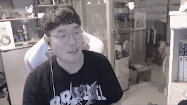 a man wearing glasses and ear buds is sitting in a room .