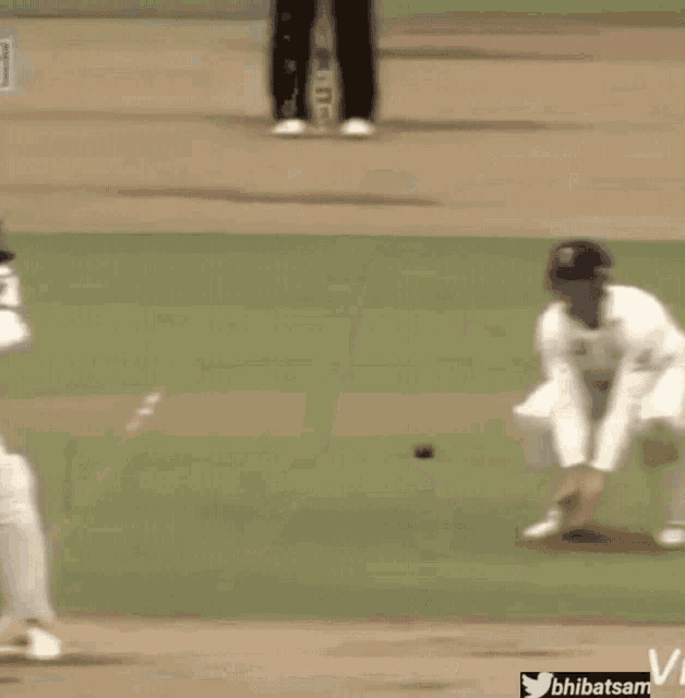 a man in a white shirt is swinging a bat at a ball