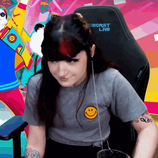 a woman wearing a secret lab t-shirt sitting in a chair