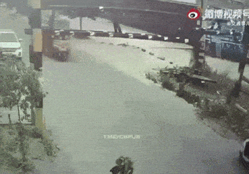 a car is driving under a bridge and a motorcycle is going underneath it .