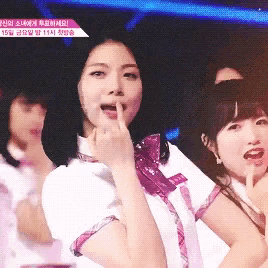 a girl in a white shirt with a purple bow on her neck holds her finger to her lips