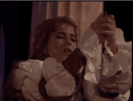 a woman in a white dress is holding a snake in her hand in a dark room .
