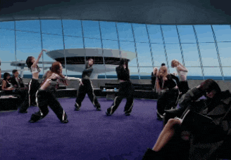 a group of people are dancing in a room with a large window