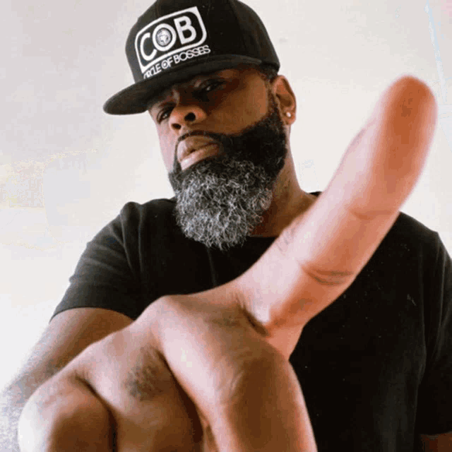 a man with a beard wears a hat that says cob