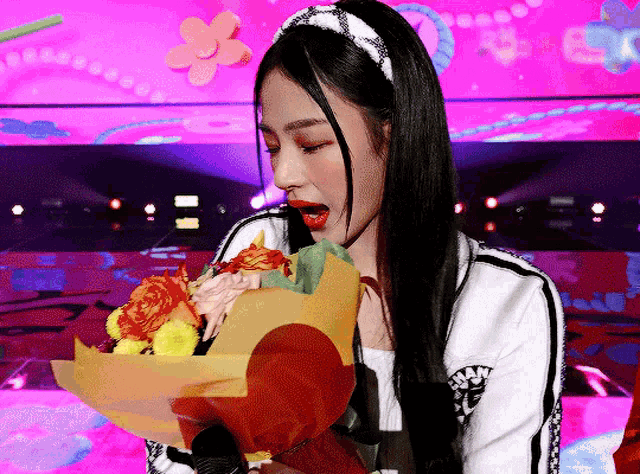 a woman wearing a headband is holding a bouquet of flowers in her hand