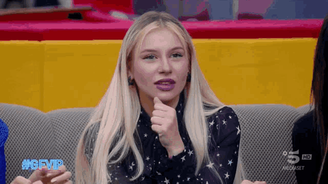a blonde woman sitting on a couch with the hashtag #gfvip on her face