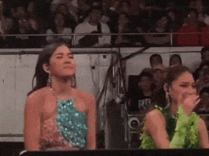two women are standing next to each other in front of a crowd of people .