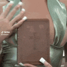 a woman is holding a bible with a cross on it in front of her chest .