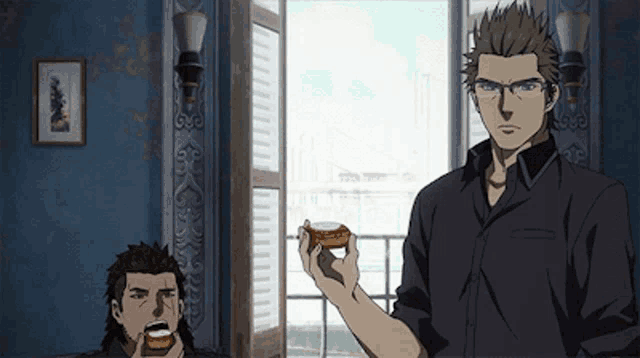 a man in a black shirt is holding a piece of food in front of a window