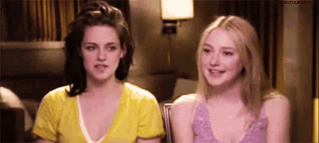two women are sitting next to each other in a room and one is wearing a yellow shirt