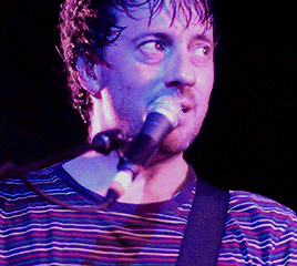 a man is singing into a microphone in a dark room