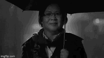 a black and white photo of a woman holding an umbrella .