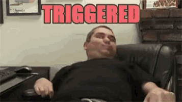 a man is sitting in a chair with the word triggered behind him