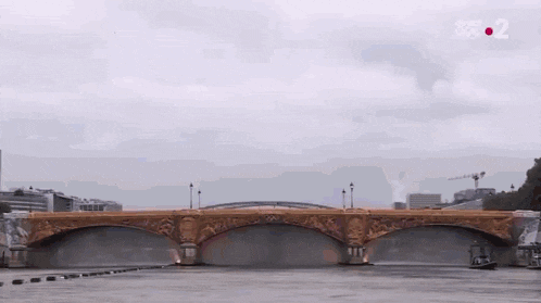 a bridge over a body of water with a boat in the background .