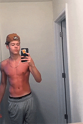 a shirtless young man is taking a selfie in the mirror .
