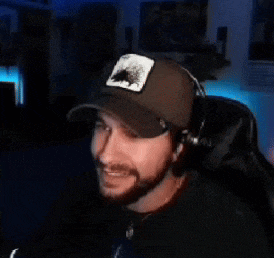 a man with a beard wearing a hat and headphones is sitting in front of a microphone .