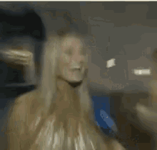 two blonde women are talking to each other in a room
