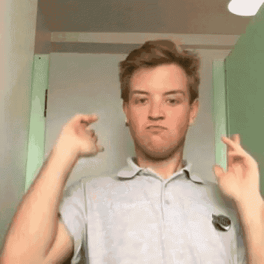 a young man in a polo shirt is making a funny face while standing in front of a green door .