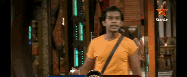 a man in an orange shirt is standing in front of a star channel