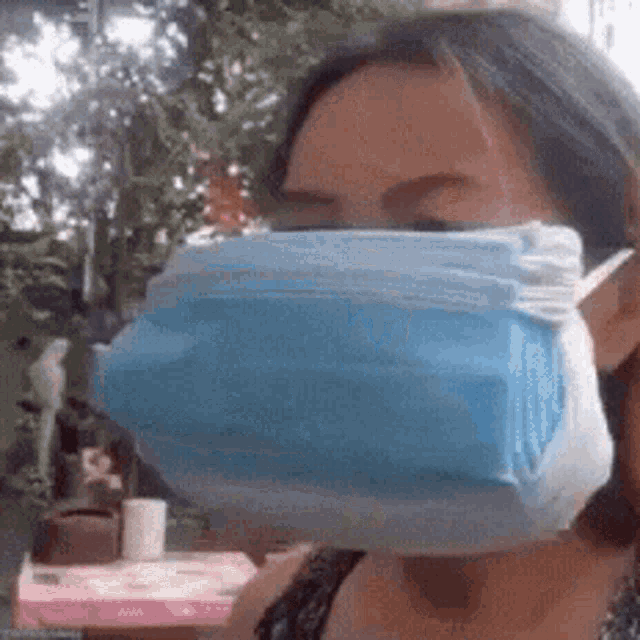a woman wearing a blue face mask is standing in front of a table .