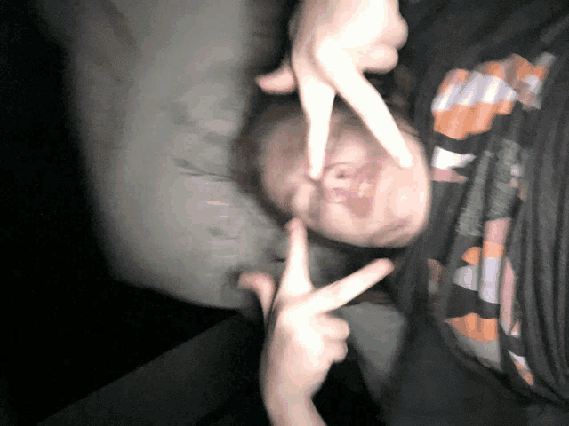 a person laying on their back giving the peace sign