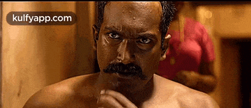 a man with a mustache is looking at the camera .