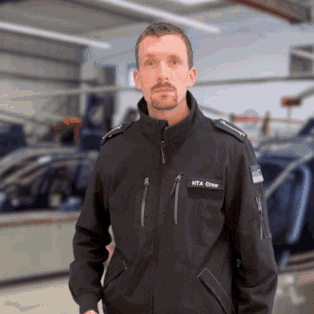 a man wearing a jacket that says hta crew on it