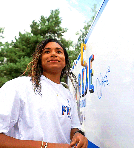 a woman wearing a white shirt with the word pride on the front