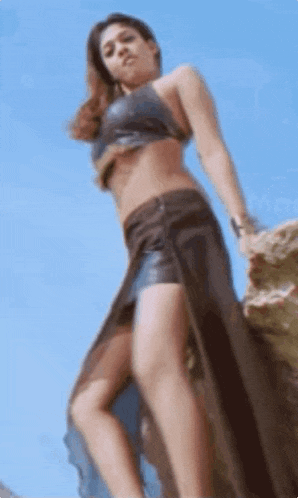 a woman in a bikini is standing on top of a rock .