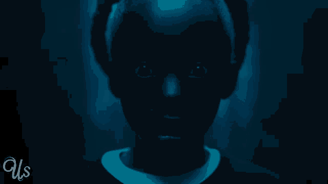 a person 's face is shown in a dark room with us written on the bottom right corner